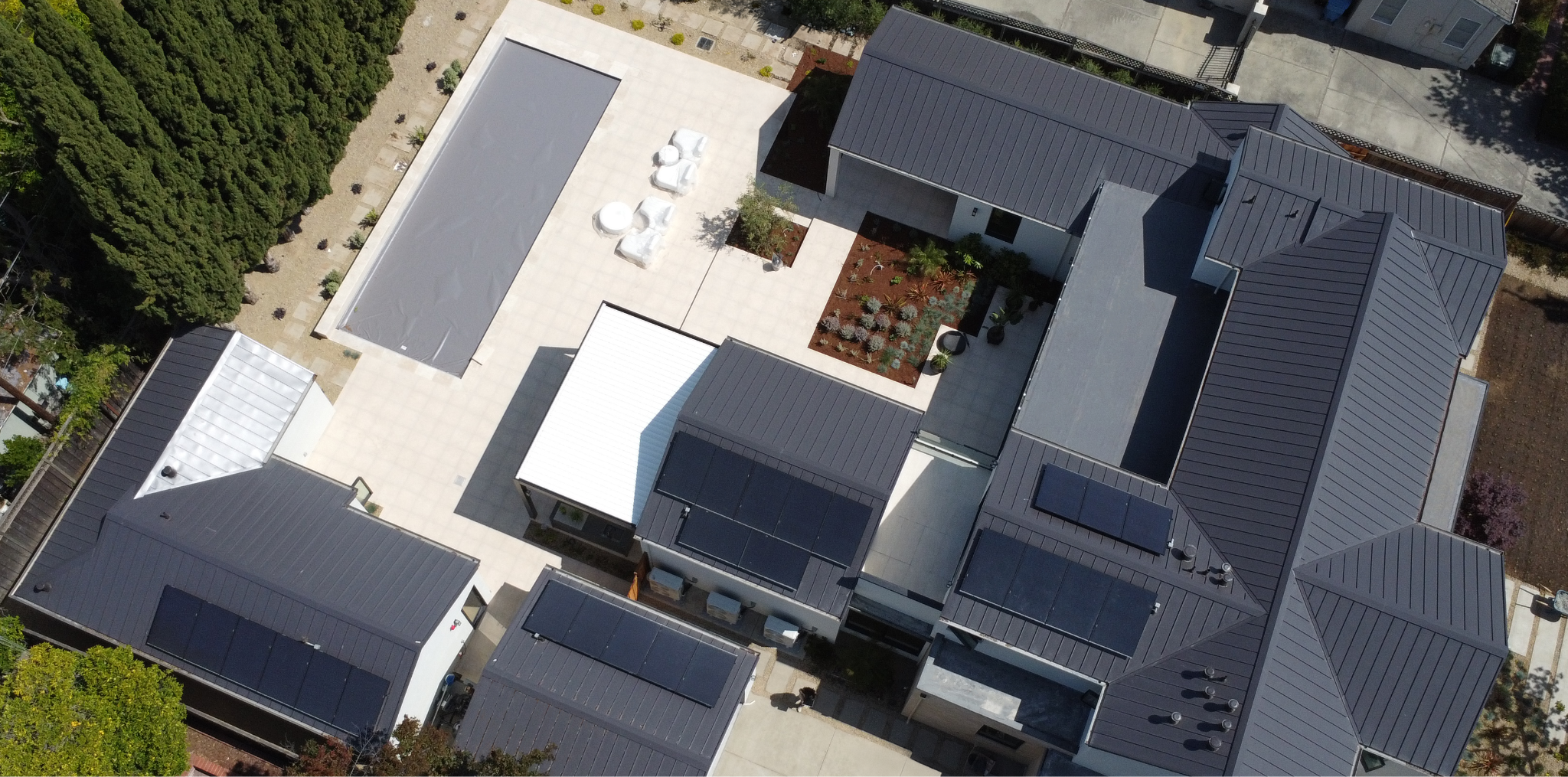 Modern home with a dark metal roof and multiple solar panel arrays