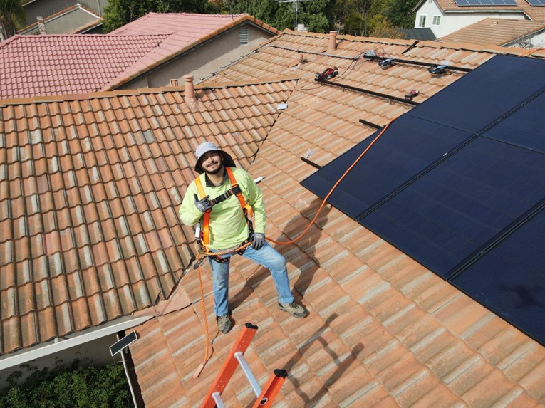Infinium technician installing solar panels on the rooftop of a home